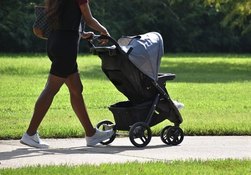 Mother pushing her child in a stroller at the park.