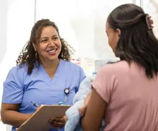 A medical professional with a clipboard talking to a woman