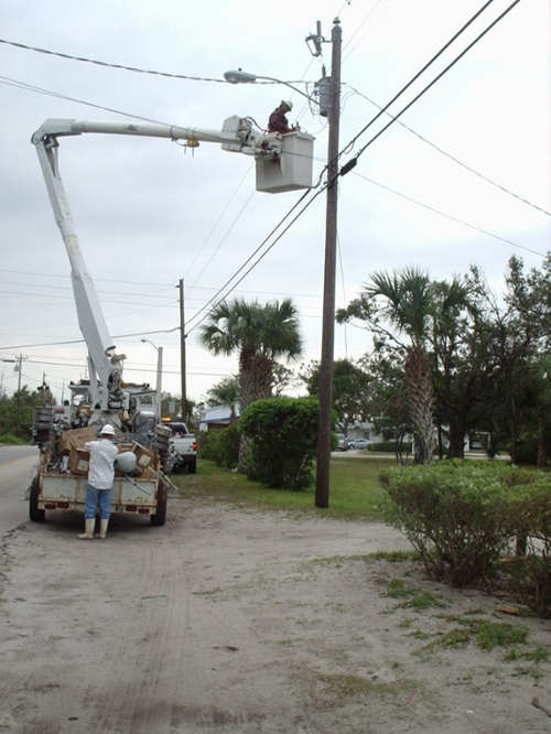 Photograph of power company employees installing electrical lines near the Wabasso Satellite Site