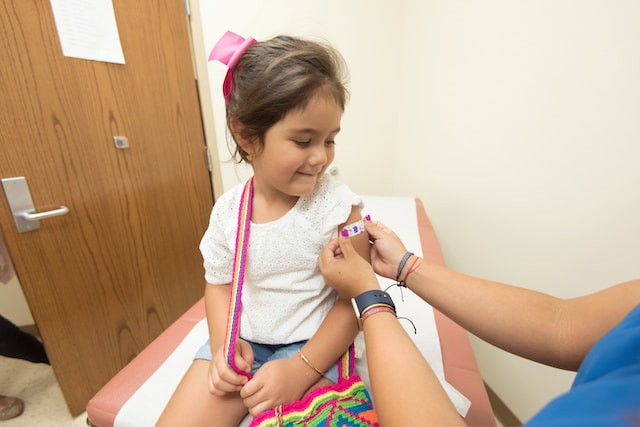 Child having an adhesive bandage placed over a vaccination site.