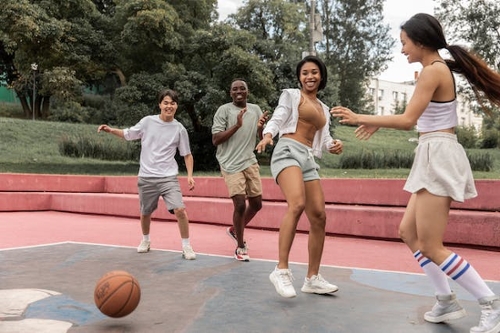 Delighted multiethnic friends playing basketball at the park.
