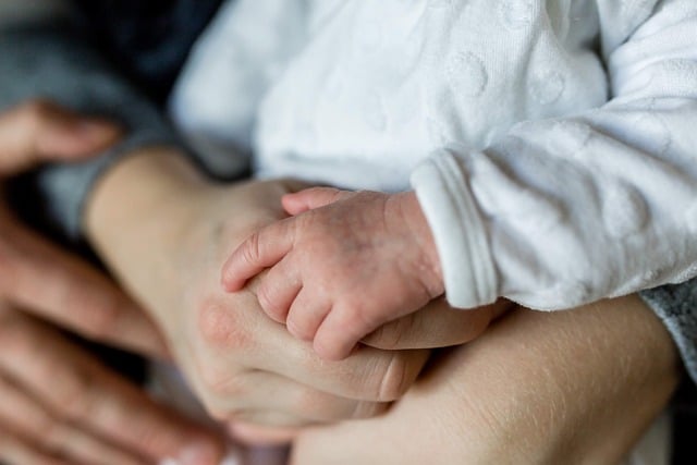Image of a baby and parent holding hands