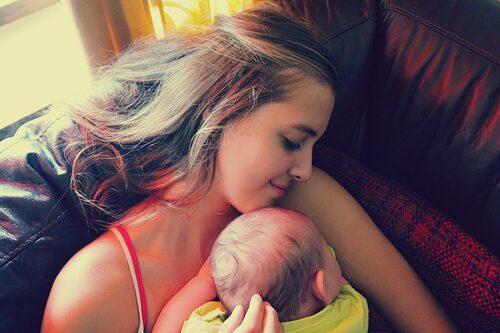 Young woman laying on couch with baby